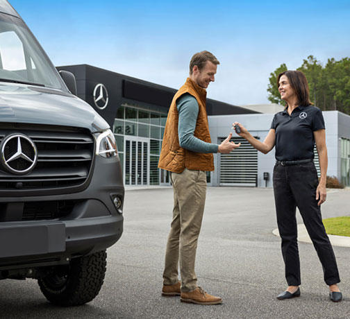 Mercedes-Benz commercial vehicle specialist handing keys to a customer outside a dealership