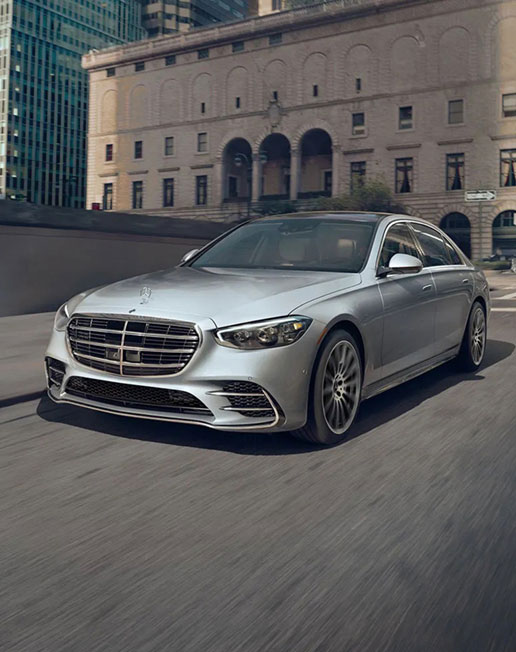 Mercedes-Benz S-Class luxury sedan driving through a downtown urban environment