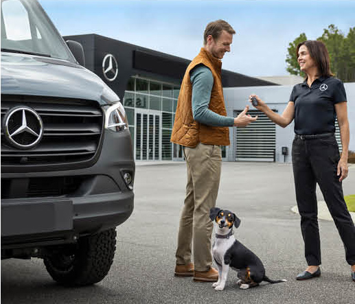 Customer receiving keys for a Mercedes-Benz Sprinter van at dealership with dog