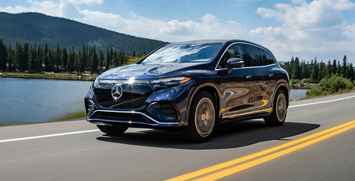 Mercedes-Benz electric SUV driving on scenic road near lake and mountains