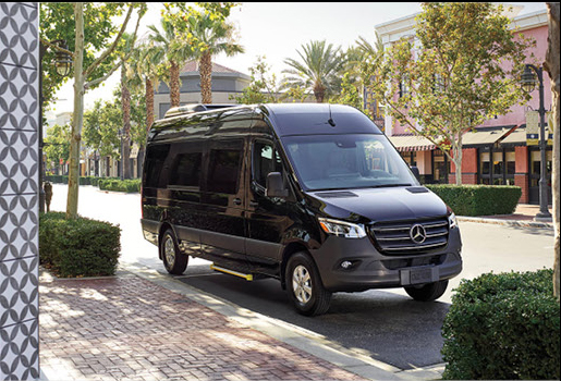 Black Mercedes-Benz Sprinter passenger van parked on upscale shopping street