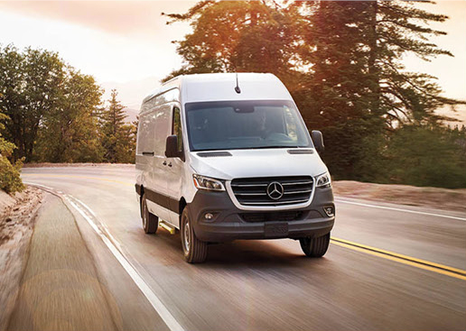 Mercedes-Benz Sprinter cargo van driving on a scenic roadway showcasing commercial transportation capability