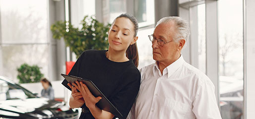 car dealership representative reviewing vehicle information with older customer