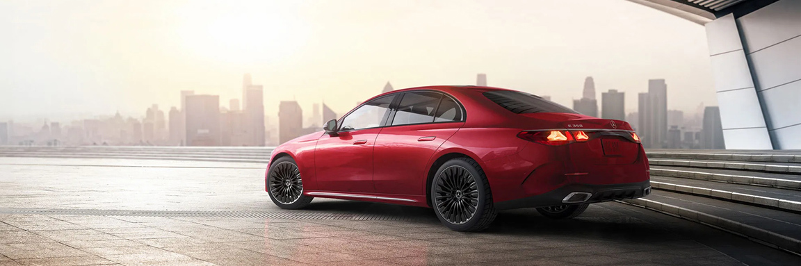 Red Mercedes-Benz vehicle parked overlooking city skyline