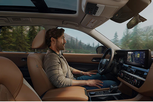 Driver seated inside the Nissan Pathfinder demonstrating ergonomic seating, advanced technology, and long-distance comfort
