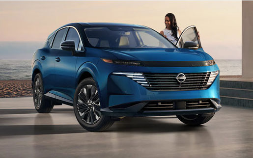 Blue Nissan electric crossover parked by the beach with driver exiting vehicle