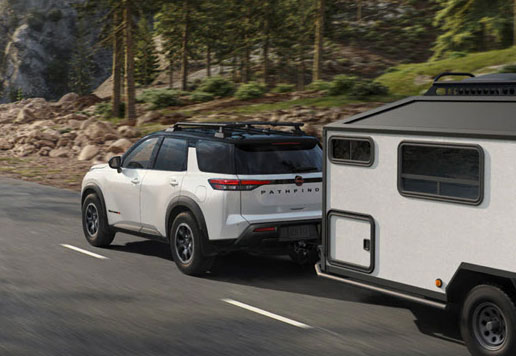 Nissan Pathfinder towing camper trailer on scenic forest road