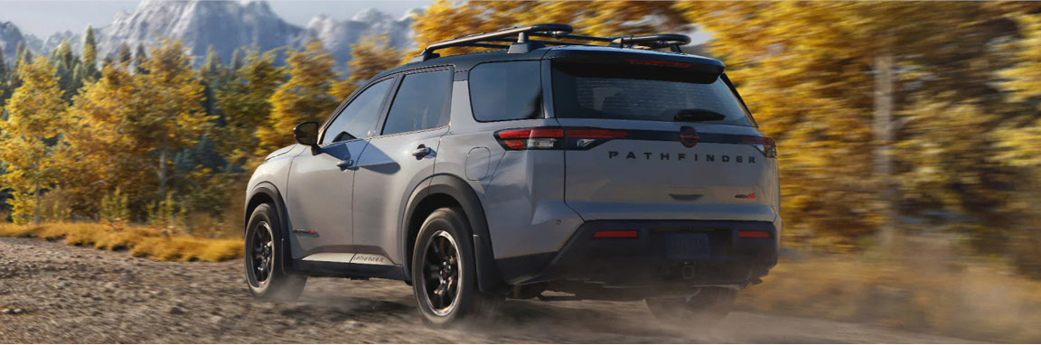 Nissan Pathfinder Rock Creek driving off-road on dirt trail with trees and mountains