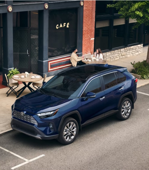 blue Toyota RAV4 SUV parked outside a local café in a walkable urban neighborhood