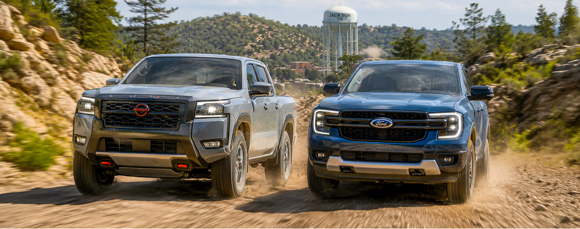 Nissan Frontier and Ford F-150 pickup trucks driving side by side on a dirt road