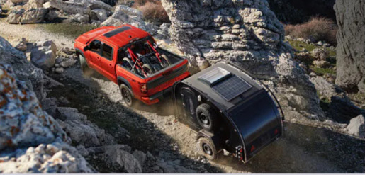 red Nissan Frontier PRO-4X towing an off-road camper trailer on a rugged mountain trail