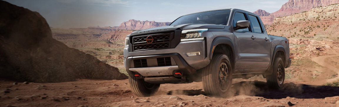 gray Nissan Frontier PRO-4X pickup truck driving across rocky desert terrain
