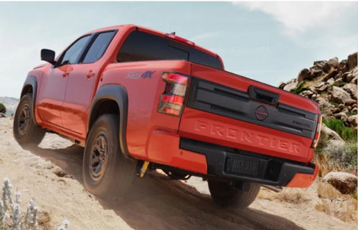 Rear view of the Nissan Frontier PRO-4X navigating a dirt trail, highlighting durable truck design and off-road performance