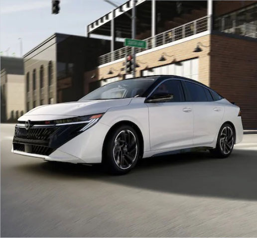 White Nissan Sentra SR sedan driving through a downtown city street showcasing modern exterior styling and sporty design
