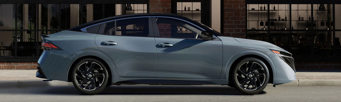 Gray Nissan Sentra sedan side profile parked in front of an urban building highlighting sleek fastback-inspired styling