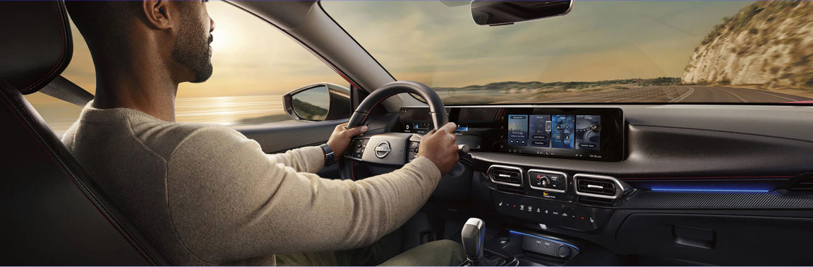 Driver inside the Nissan Sentra using the digital instrument cluster, widescreen infotainment display and modern interior technology while driving