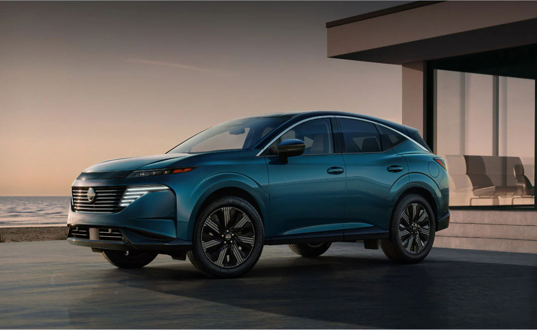 Nissan Ariya electric SUV parked near a modern coastal home at sunset