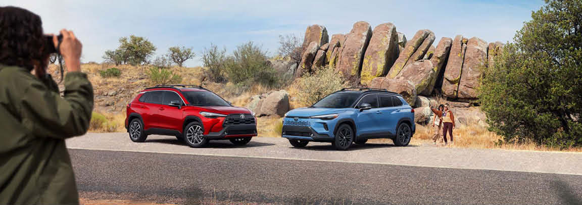 Toyota SUVs parked in desert landscape with rocky backdrop and family nearby