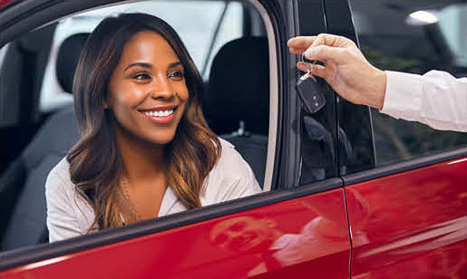 happy customer receiving car keys inside new vehicle at dealership