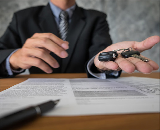 Dealer handing over car keys after signing vehicle purchase agreement