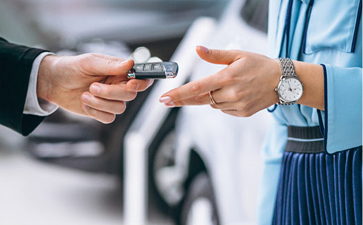 Close-up of handing over car key fob during vehicle purchase transaction
