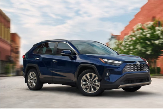 Blue Toyota RAV4 driving in city with modern styling and smooth performance