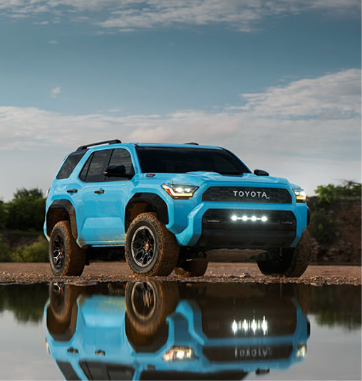 blue Toyota 4Runner TRD Pro SUV parked near a calm body of water with off-road lighting