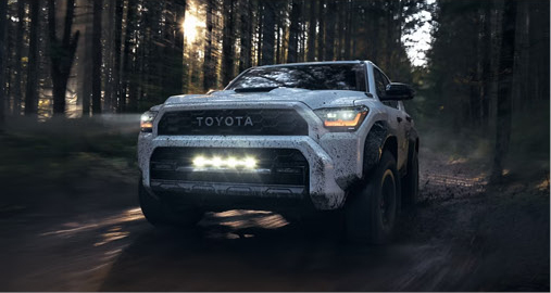 white Toyota Tacoma TRD Pro pickup truck driving through a wooded off-road trail
