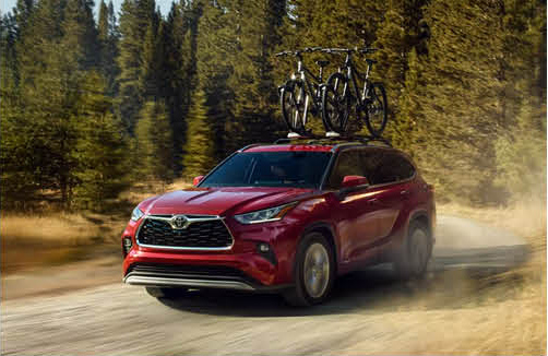 Toyota Highlander driving on a forest road with bicycles mounted on the roof