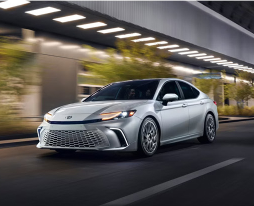 Toyota Camry driving through a modern city at night highlighting sleek sedan styling and confident performance