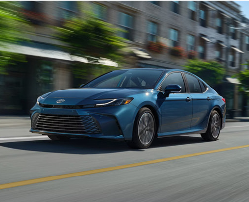 Toyota Camry sedan driving through a downtown area demonstrating smooth everyday commuting performance