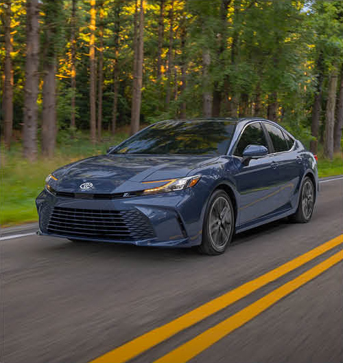 Toyota Camry sedan driving on a scenic forest road