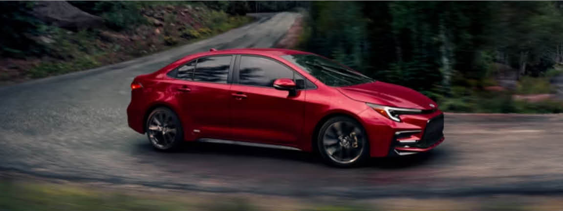 Toyota Corolla sedan driving along a winding mountain road