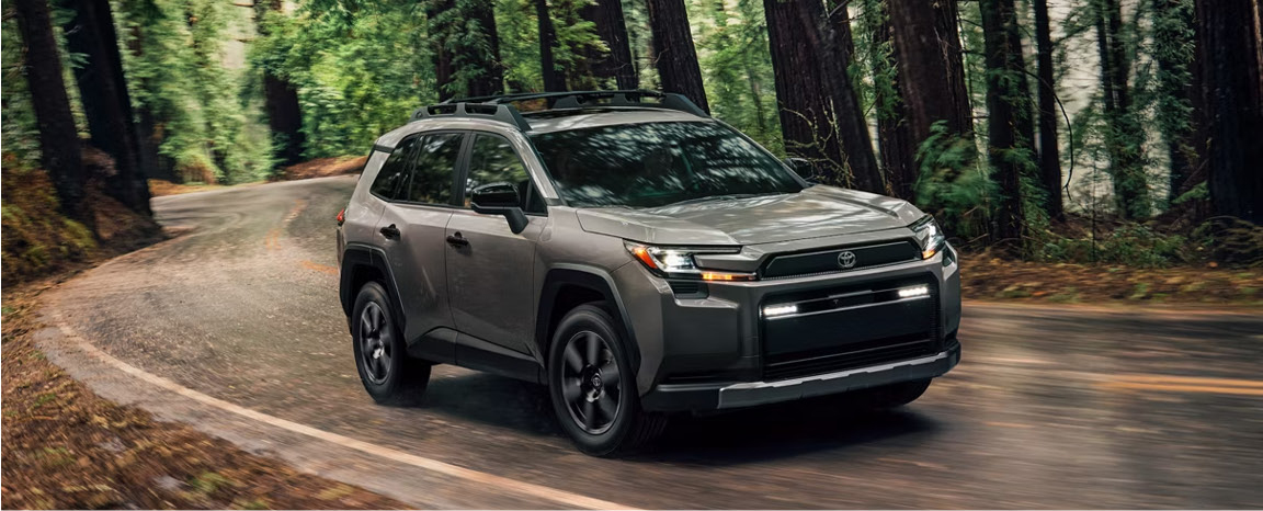 Toyota RAV4 SUV driving along a winding road through a dense forest