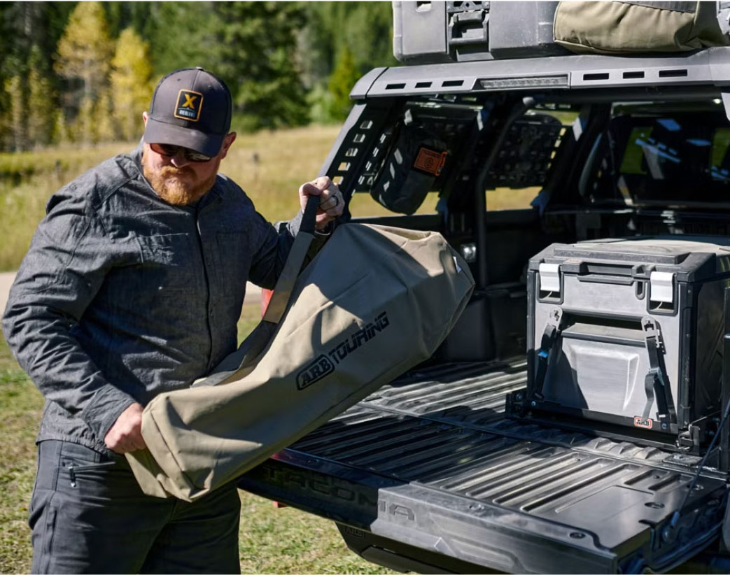 a man unloading camping gear from his Toyota Tacoma pickup