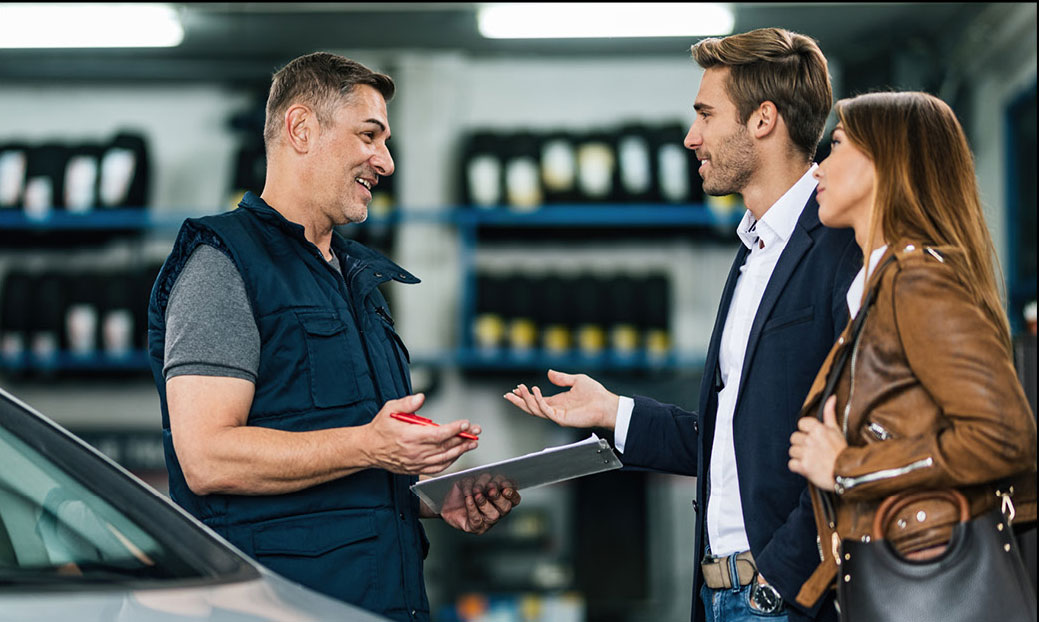 Service technician talking with customers at automotive service center