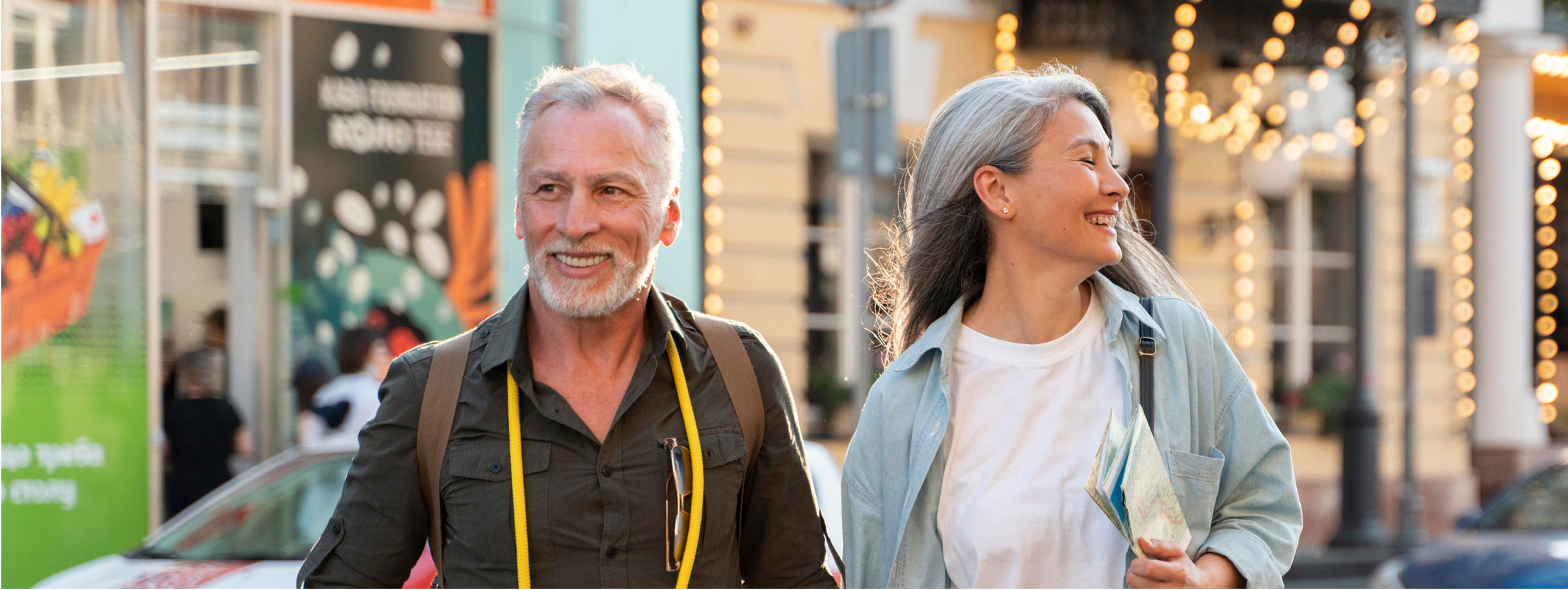 Older couple walking happily together through city street at sunset