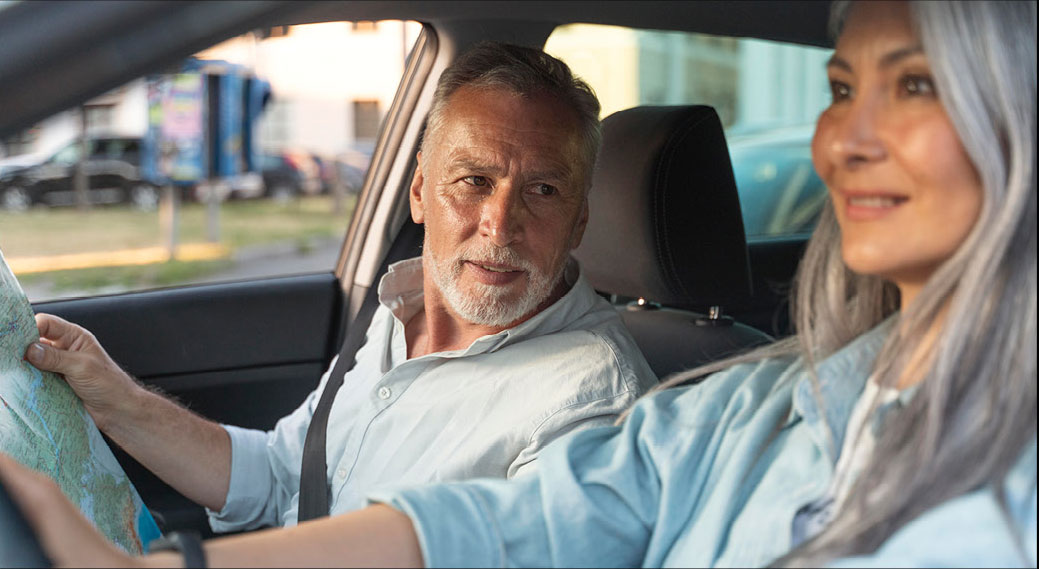 Older couple navigating with map while sitting inside parked car