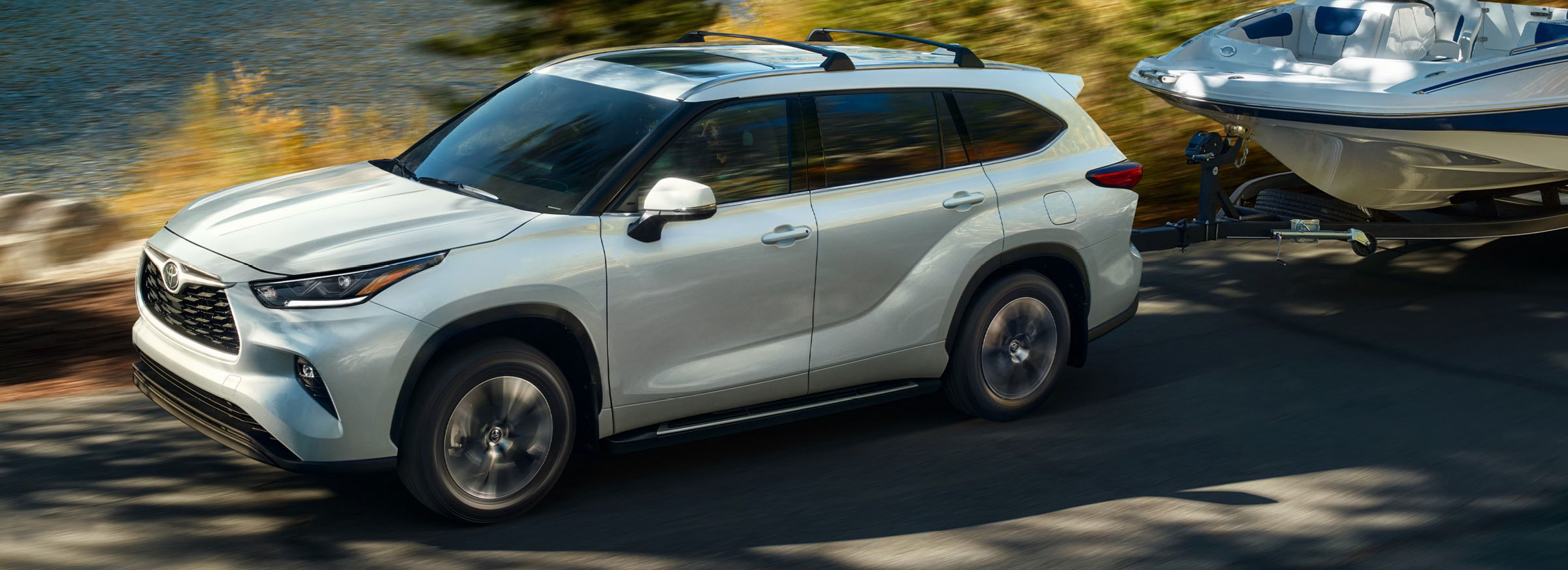 Toyota Highlander towing a boat on a scenic lakeside road