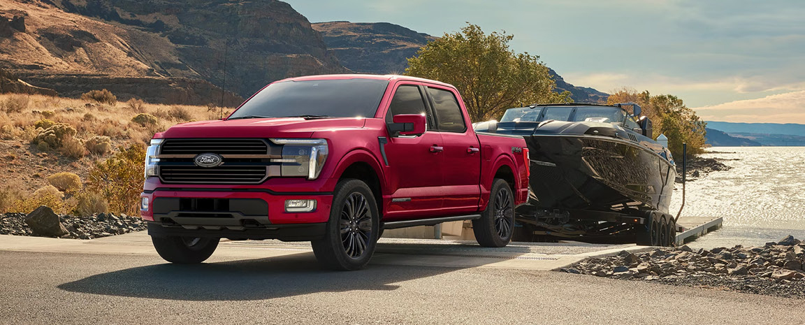 Ford F-150 pickup towing a boat at a lakeside launch ramp