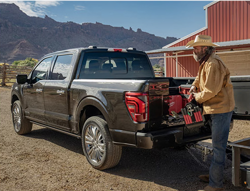Ford F-150 tailgate workspace with tools and gear on a ranch
