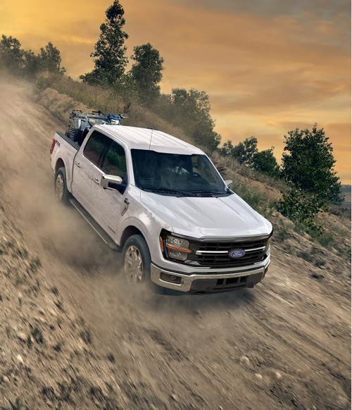 Ford F-150 pickup driving off-road on dusty hillside terrain