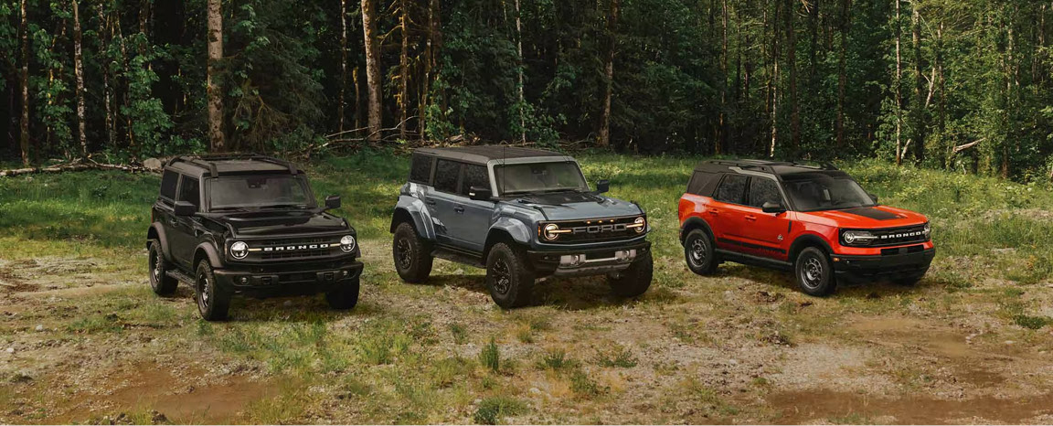 Ford Bronco lineup in forest featuring multiple trims and colors off-road