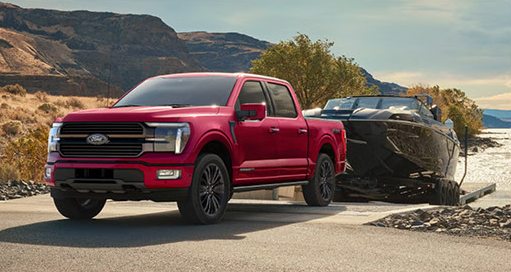 Ford F-150 towing a large boat on a trailer near the water