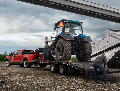 Ford Super Duty truck towing a tractor on a flatbed trailer