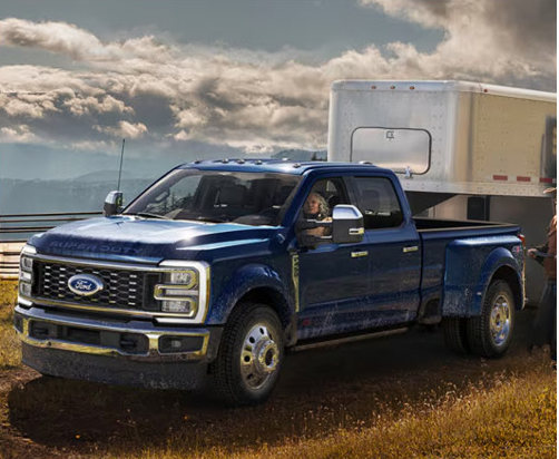 Ford Super Duty dually truck towing a large cargo trailer in a rural landscape