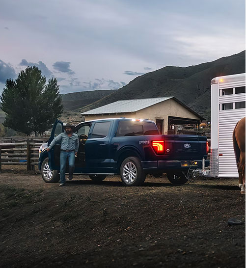 Ford F-150 parked at a ranch while towing a horse trailer, demonstrating dependable towing capability and rural lifestyle versatility
