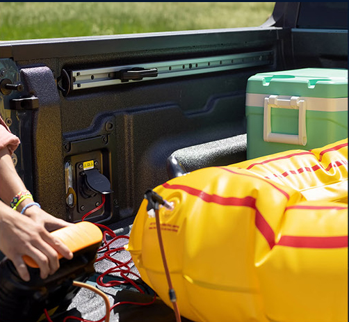 Ford Maverick truck bed featuring built-in power outlet, cooler, and outdoor adventure equipment