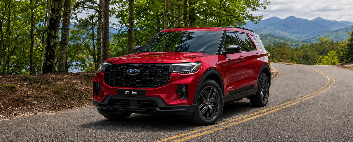 red Ford Explorer ST-Line SUV parked on a scenic mountain roadway surrounded by forest views