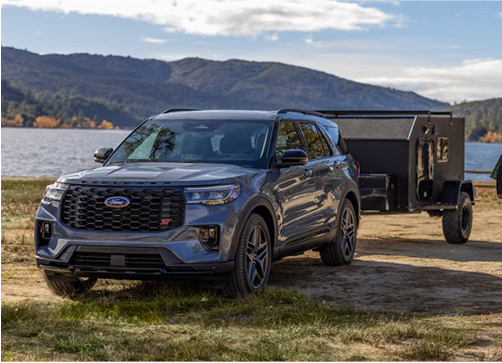 blue Ford Explorer SUV towing a utility trailer near a lakeside campsite